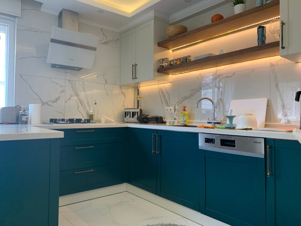 Modern Villa İç Mimarlık Projesi Mermer desenli tezgah, koyu renk mutfak dolapları ve modern ankastre beyaz eşyaların görüldüğü, tamamlanmış mutfağın gerçek fotoğrafı.