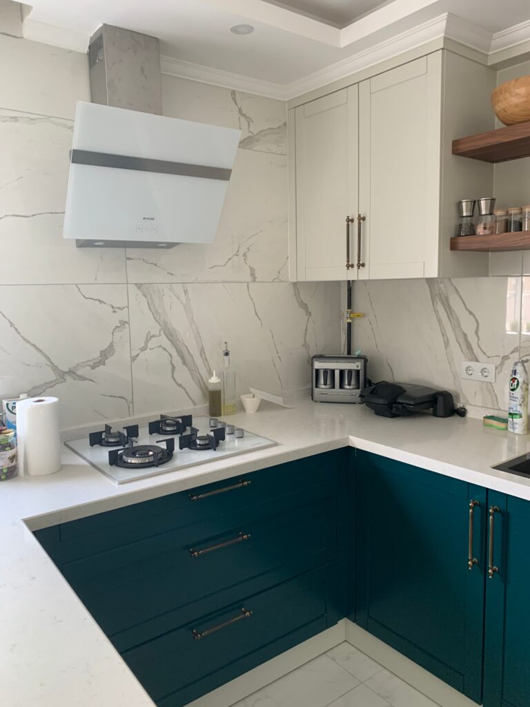 Modern Villa İç Mimarlık Projesi Mermer duvar panelleri ve modern ocak davlumbazıyla tasarlanmış, mutfak tezgahının gerçek fotoğrafı.