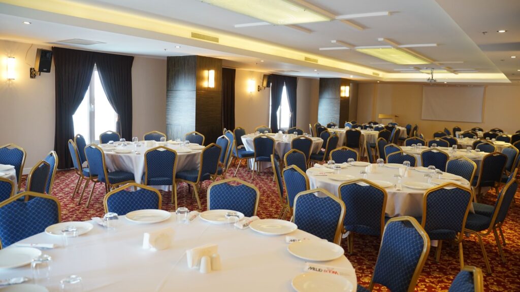 Melid Otel İç Mimarlık Yuvarlak masalar ve mavi sandalyelerle, şık bir etkinlik veya toplantı salonu dekorasyonu.