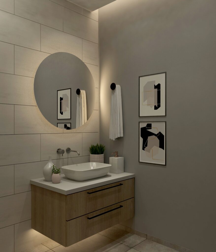 Yuvarlak, aydınlatmalı ayna, ahşap banyo dolabı ve modern sanat tablolarıyla minimalist banyo.